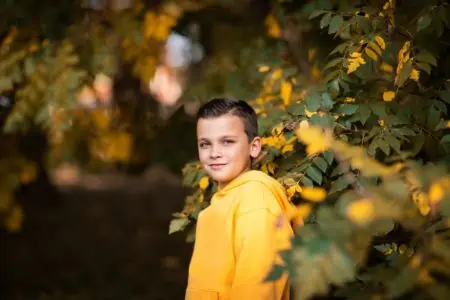 Cute little boy in yellow hoodie spending time in the park
